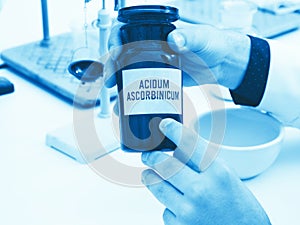 A scientist holds a bottle of ascorbic acid with an inscription in Latin: Acidum ascorbinicum photo