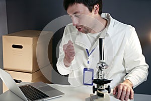 Scientist in lab coat and eyeglasses working at workplace with laptop in laboratory. Male doctor researcher are doing