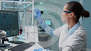 Scientist in laboratory analyzing petri dish with liquid bacteria