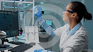 Scientist in laboratory analyzing petri dish with liquid bacteria