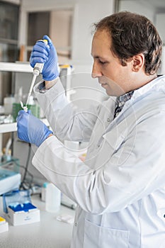 Scientist in the laboratory filling test tubes with pipette