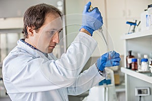 Scientist in the laboratory filling test tubes with pipette