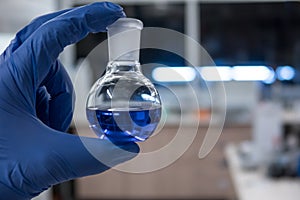 Scientist in a laboratory holding a flask containing a purple chemical. Titration analysis