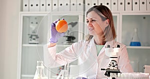 Scientist in the laboratory looks at orange citrus fruit closeup