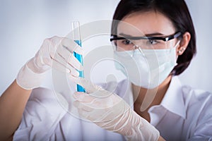 Scientist looking at blue test tube in the laboratory.