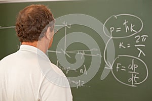 Scientist looking at formula on blackboard