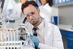 Scientist Looking Through Microscope In Laboratory, Male Researcher Doing Research Experiments