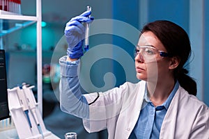 Scientist looking at testube with sample, analyzing liquid experiment