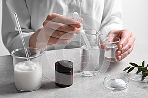 Scientist making cosmetic product at grey table in laboratory, closeup