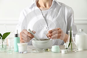 Scientist making cosmetic product at table in laboratory, closeup