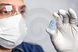 scientist man in goggles, gloves and a mask holds an ampoule of DNA, the concept of scientific molecular biotechnology, the study