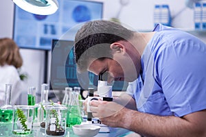 Scientist man looking through microscope after viruses in a research lab for agriculture industry