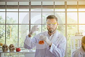 Scientist man working smelling test and putting medical chemicals sample in test tube at laboratory