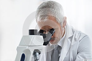 Scientist, mature man and microscope in lab for discovery, medical research and test for forensics. Male person, analyze photo