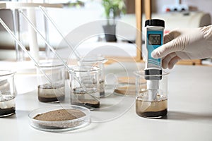 Scientist measuring acidity and pH of soil at table. Laboratory analysis