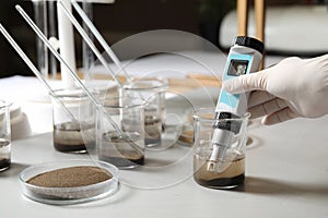 Scientist measuring acidity and pH of soil at table. Laboratory analysis