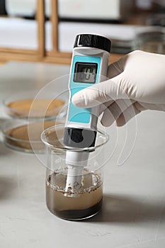 Scientist measuring acidity and pH of soil at table. Laboratory analysis