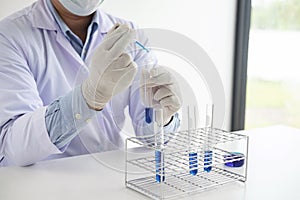 Scientist or medical in lab coat holding test tube with reagent
