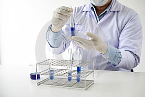 Scientist or medical in lab coat holding test tube with reagent, mixing reagents in glass flask in laboratory research