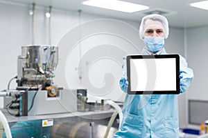 scientist near steel machine hold empty tablet, focus on tablet,