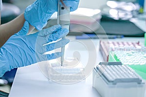 Scientist pipette dropping a sample into a test microtiter plate