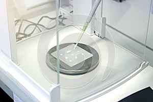 Scientist pipette a sample to sheet PMMA Poly methyl methacrylate acrylic plate on analytical balance to know the exact weight photo