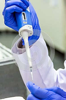 Scientist placing sample in the tube while wearing the protective gloves