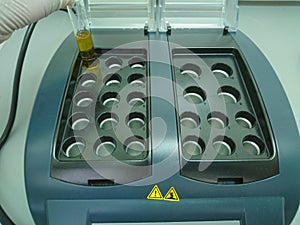 Scientist placing a test tube in a heat block