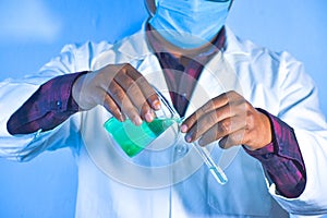 Scientist pouring color liquid from beaker into a test tube