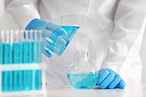 Scientist pouring color liquid into flask in laboratory