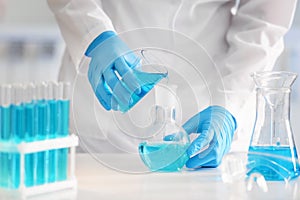 Scientist pouring color liquid into flask in laboratory