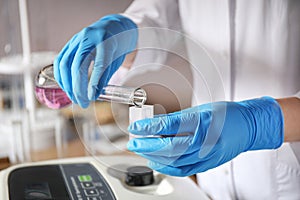 Scientist pouring colorful liquid into sample compartment in laboratory