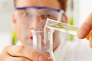 Scientist Pouring Liquid From Test Tube Into Flask