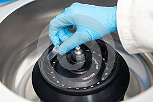 Scientist puts microcentrifuge tubes into centrifuge for phase separation