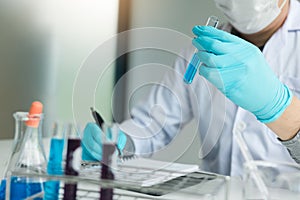 Scientist recording making note on book with his findings test tube in lab