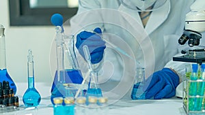 Scientist`s hand tool holding a bottle with laboratory glassware in the background of a chemistry lab. Research and development co