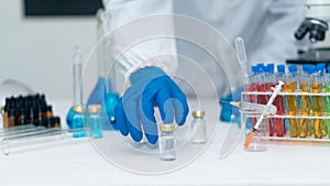 Scientist`s hand tool holding a bottle with laboratory glassware in the background of a chemistry lab. Research and development co