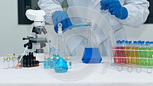 Scientist`s hand tool holding a bottle with laboratory glassware in the background of a chemistry lab. Research and development co