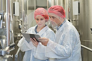 Scientist speaking to colleague holding clipboard in factory