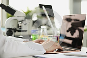 Scientist or student using laptop computer and microscope. online learning