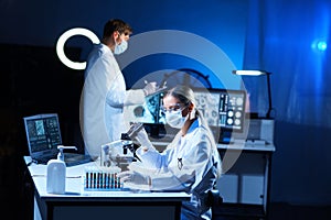 Scientist and student working in lab. Doctor teaching intern to make blood analyzing research. Coronavirus, vaccine