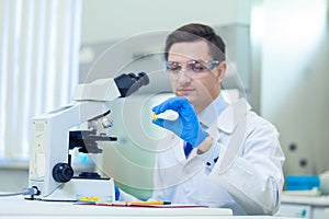 Scientist studies properties and benefits of omega 3 fatty acids using microscope and laboratory equipment in a medical