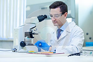 Scientist studies properties and benefits of omega 3 fatty acids using microscope and laboratory equipment in a medical