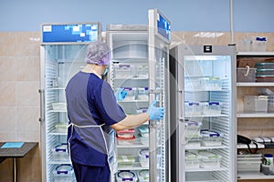 The scientist takes samples of materials for experiments out of the refrigerator