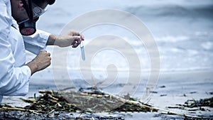 Scientist taking sample of water on seashore, health issues caused by pollution