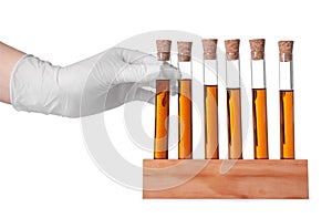 Scientist taking test tube with brown liquid from stand on white background, closeup