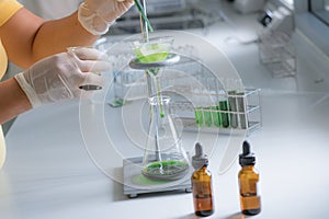 The scientist is testing the natural product extraction and green color solution, in the chemistry laboratory.
