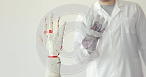 Scientist is testing robotic prosthesis hand which repeats the movement of his hand in glove with sensors. Muscle