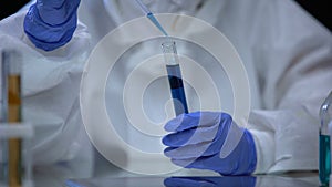Scientist of toxic lab examining sample of blue ionizing radiation liquid danger