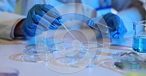 Scientist transfers test liquid from test tube using pipette to Petri dish in laboratory closeup